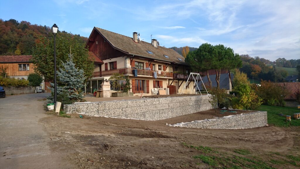 Mur de gabions réalisé en soutènement devant une maison avec aménagement du terrain.